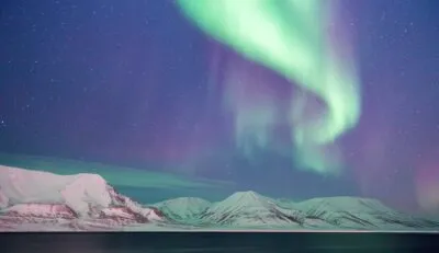 Noorderlicht boven besneeuwde bergen in Spitsbergen