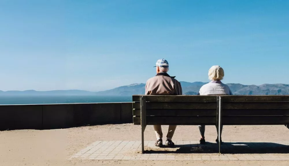 Ouderen op bankje met uitzicht op baai