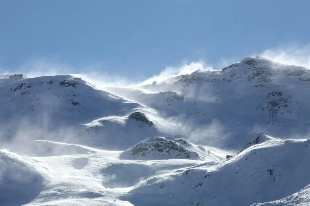 Sneeuw waait van de bergen in de Franse Alpen, Frankrijk.
