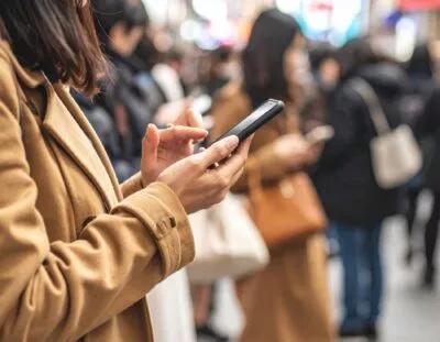 Vrouw houdt mobiel vast in stad.